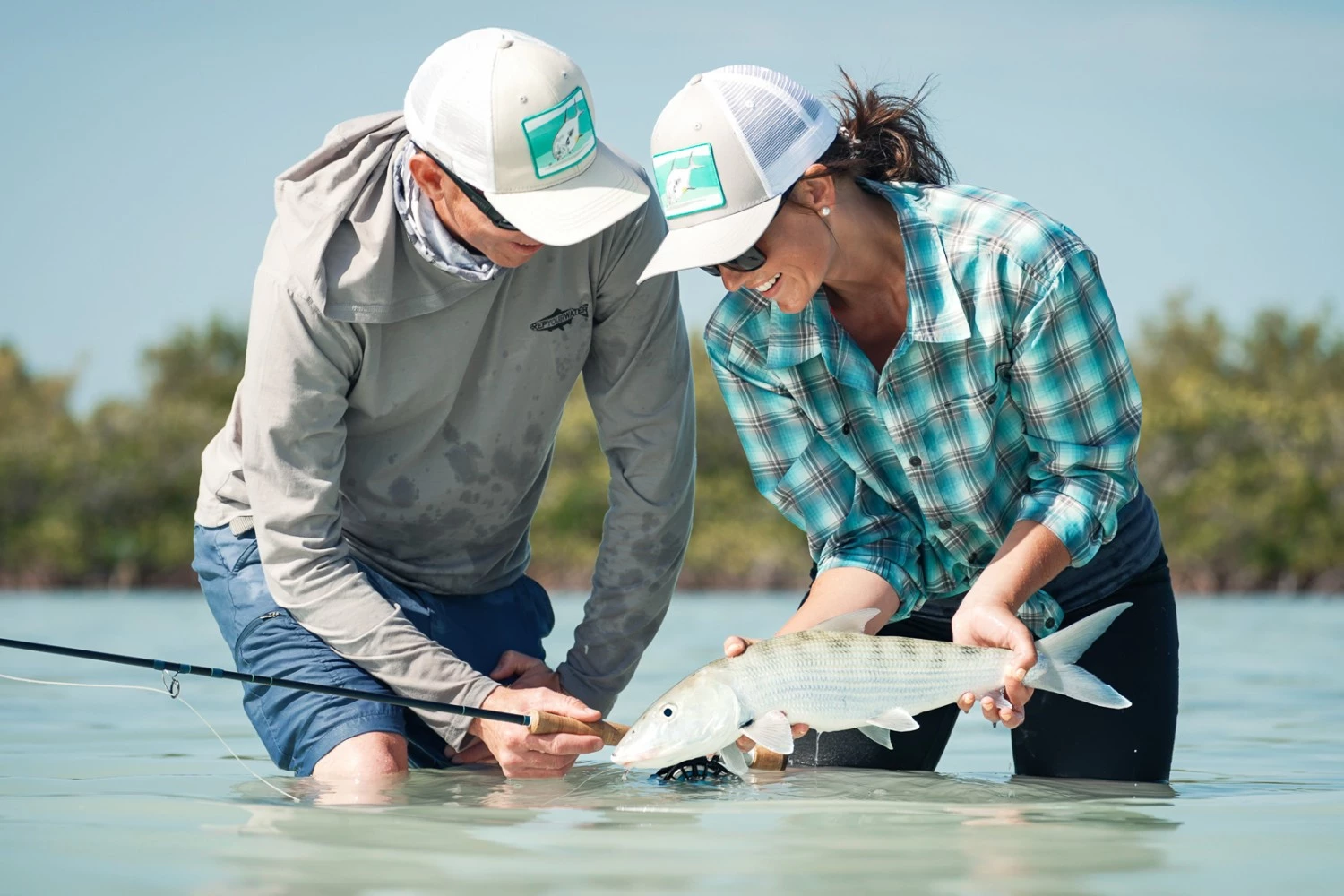 a man and woman holding a fish in water