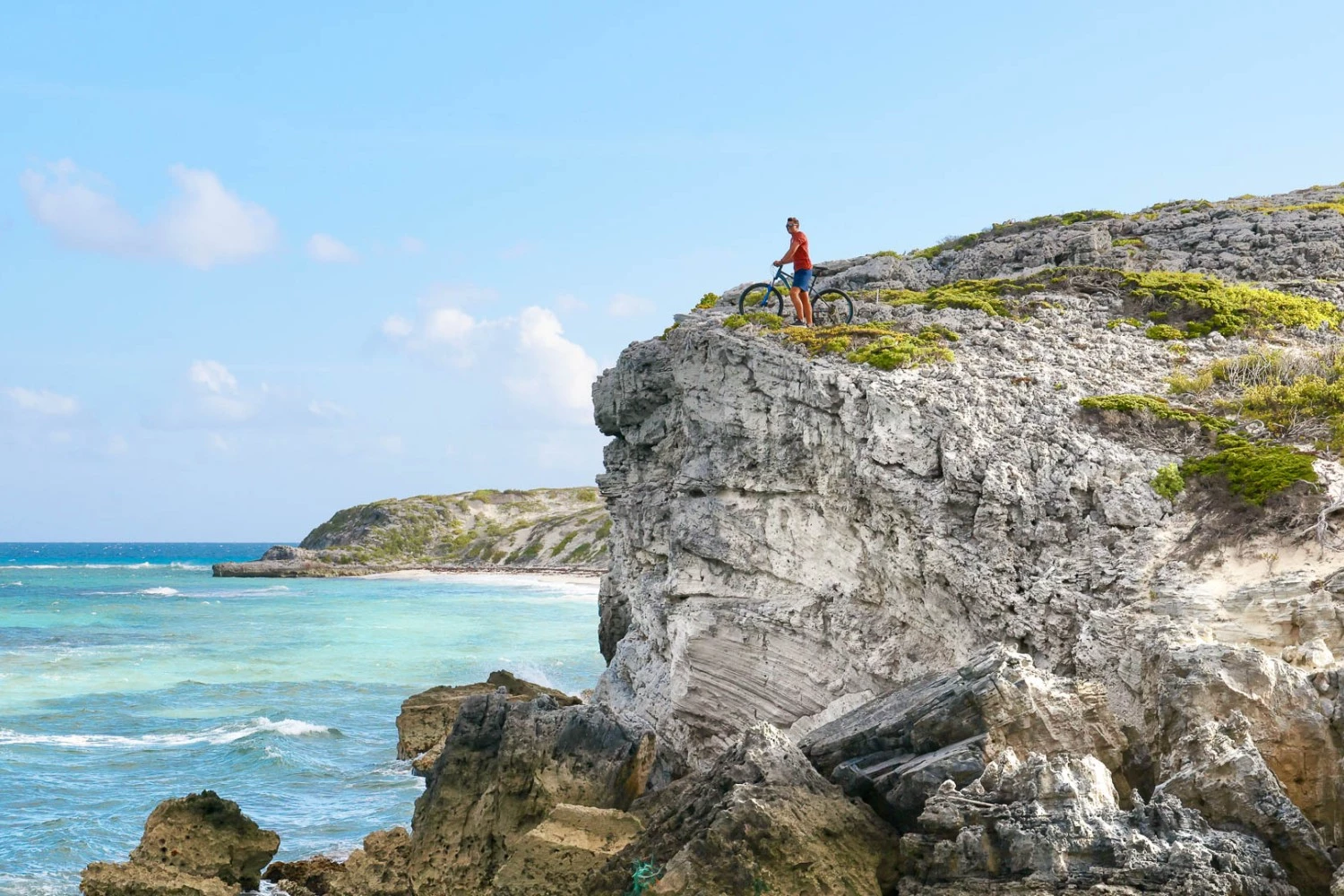 a man standing on a rocky cliff next to a body of water