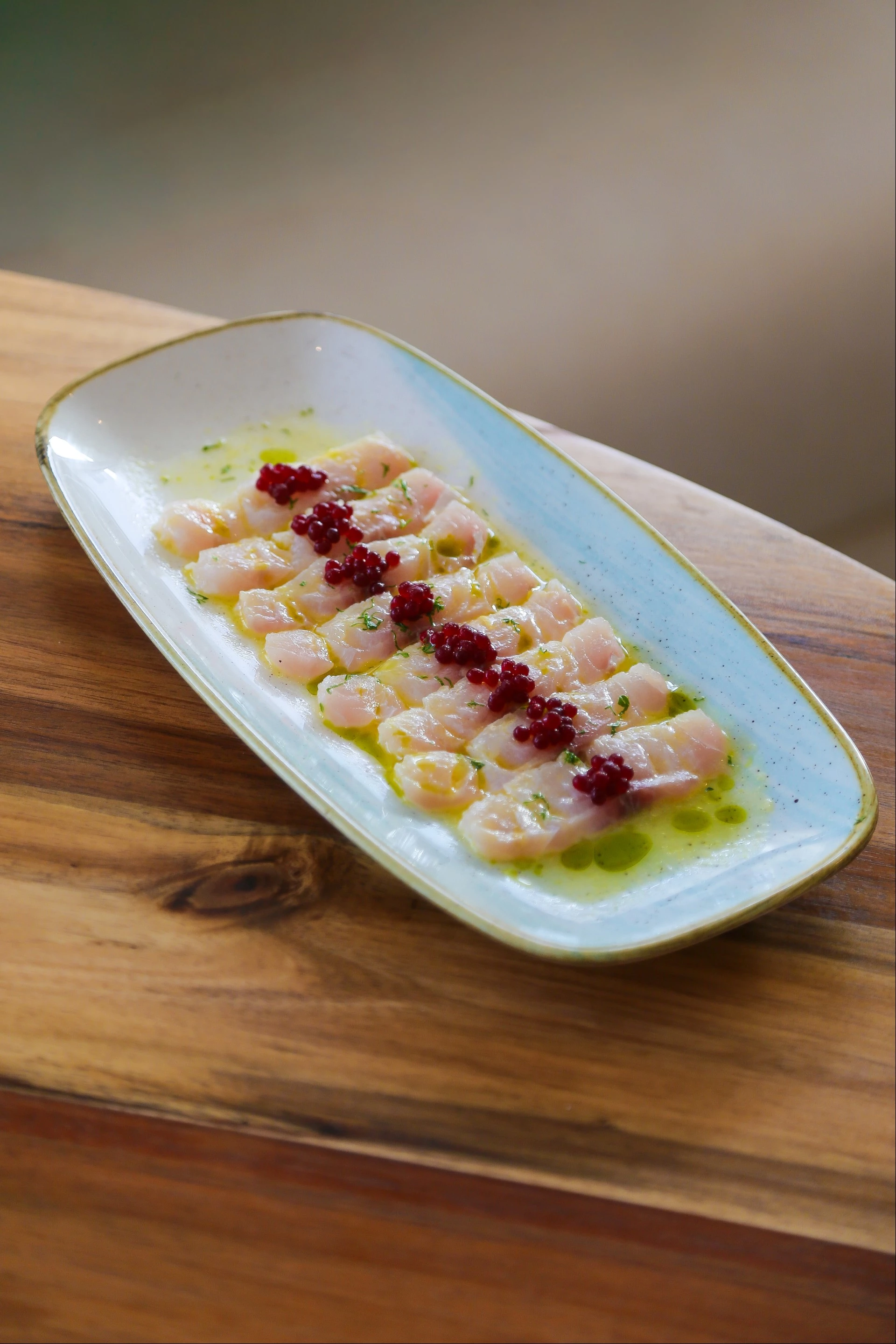 a plate of raw fish with red berries on it