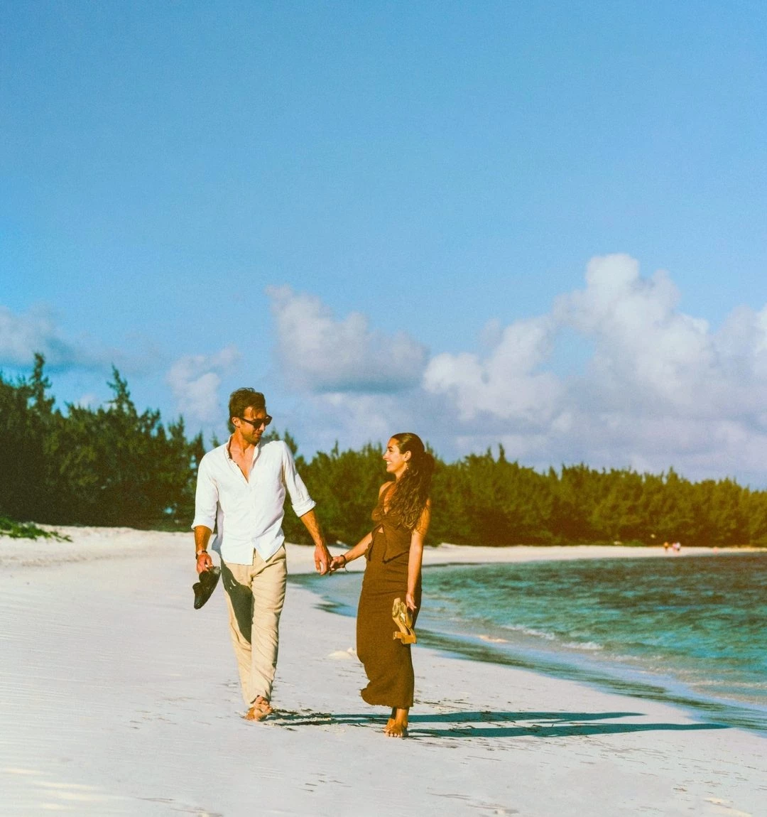 a man and woman holding hands on a beach