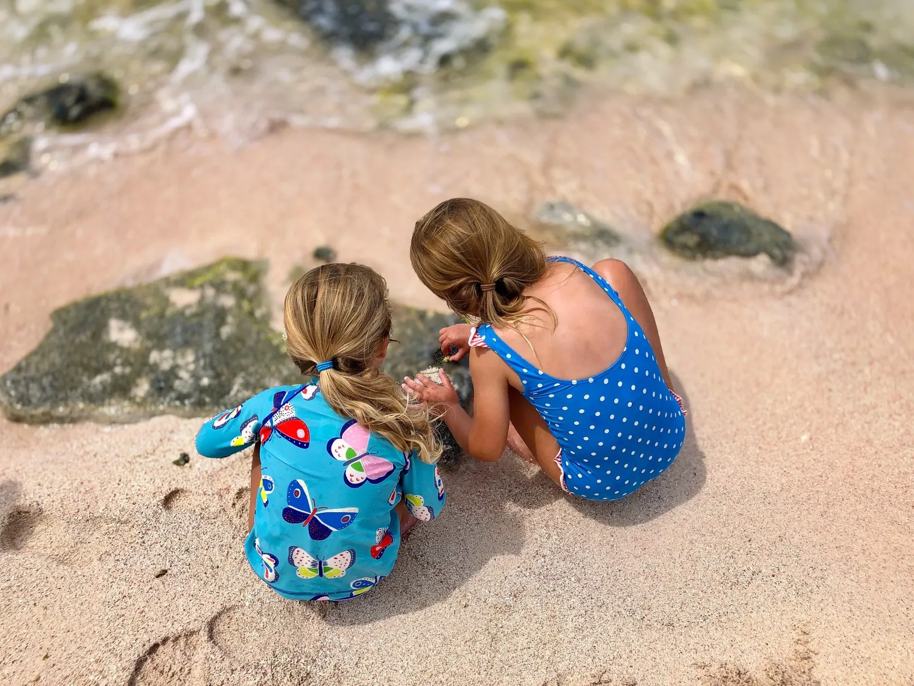 two girls sitting on the sand