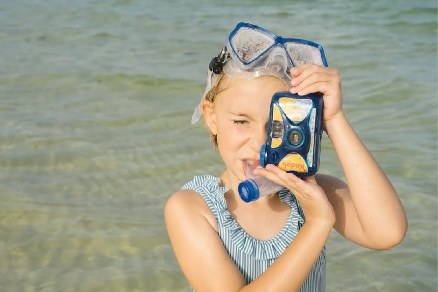 a girl holding a camera in the water