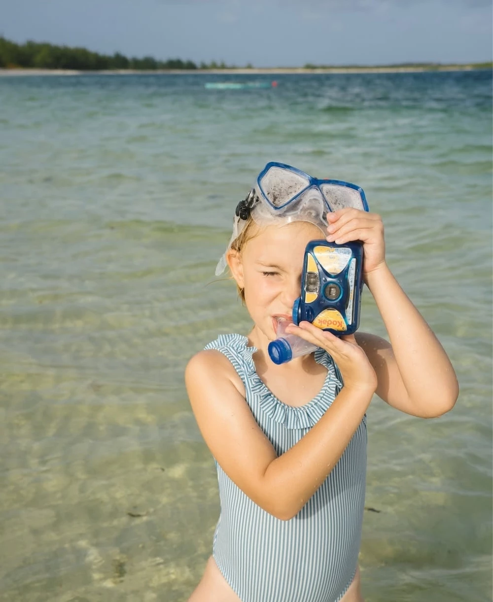 a girl holding a camera in the water