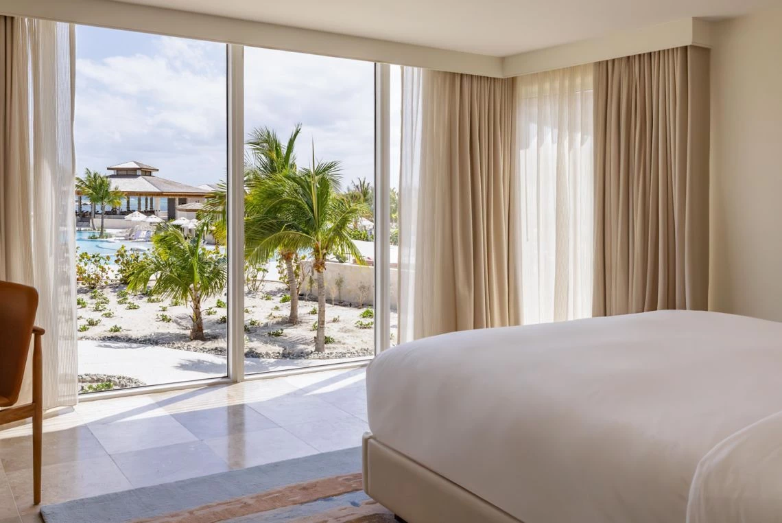 a bedroom with a view of a beach and palm trees