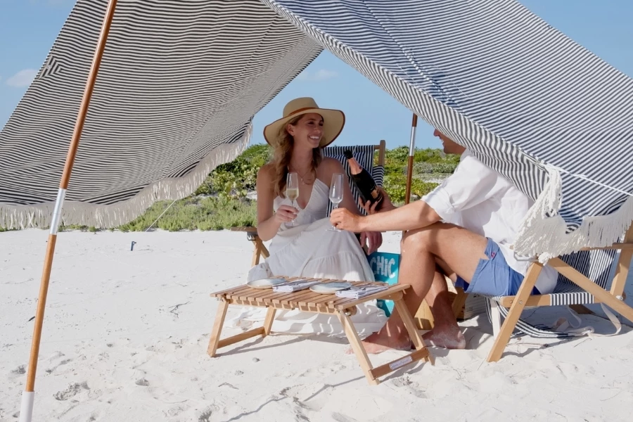 a man and woman sitting under a tent on a beach