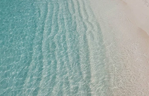 a clear blue water on a sandy beach