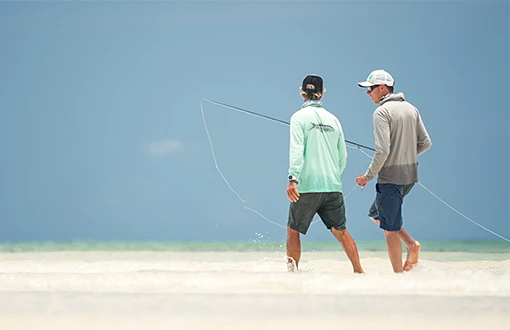a man walking on the beach with a fishing pole