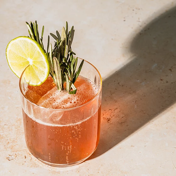 a glass with a drink and a lime on it