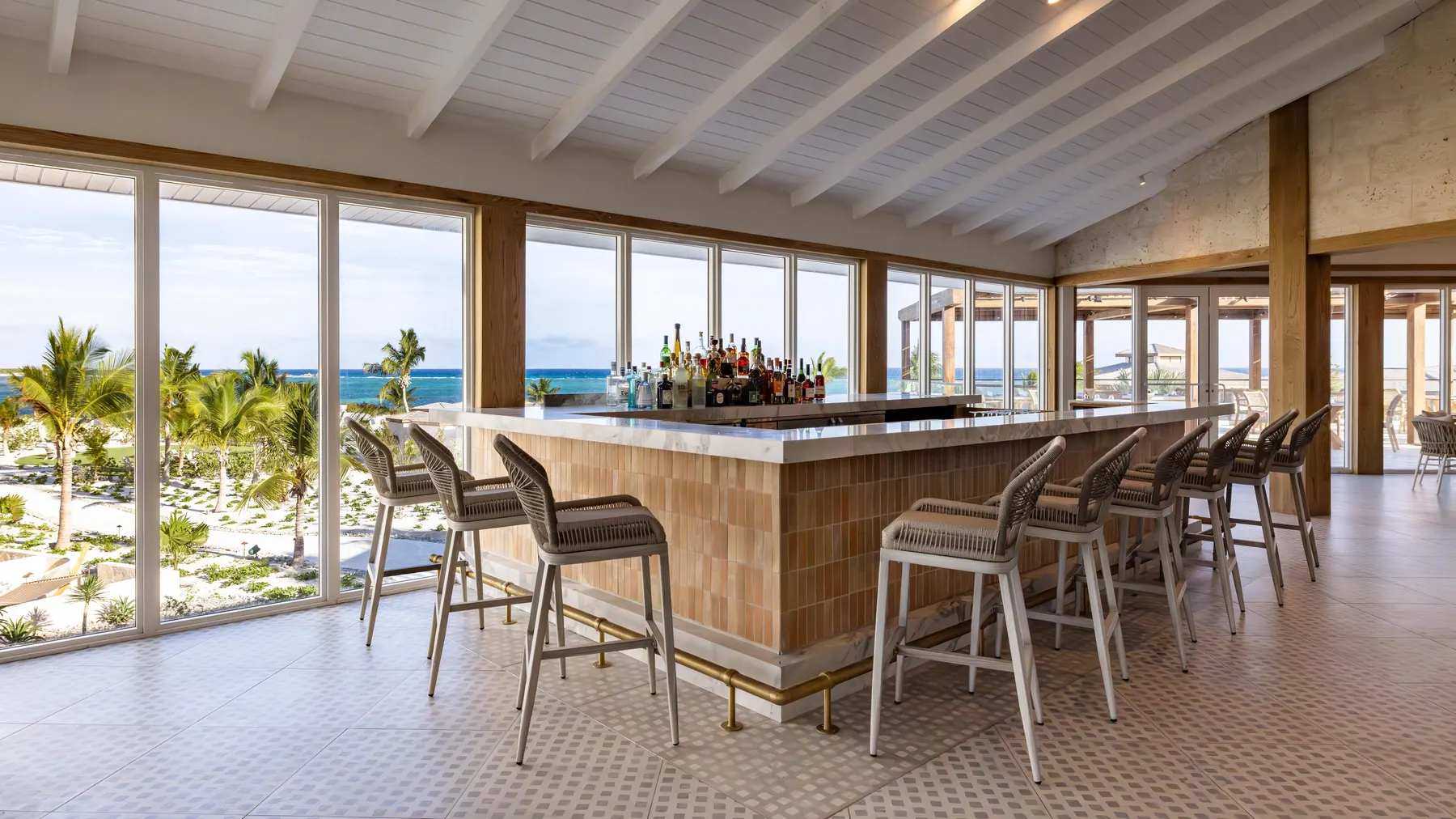 a bar with chairs and a table with a view of the ocean