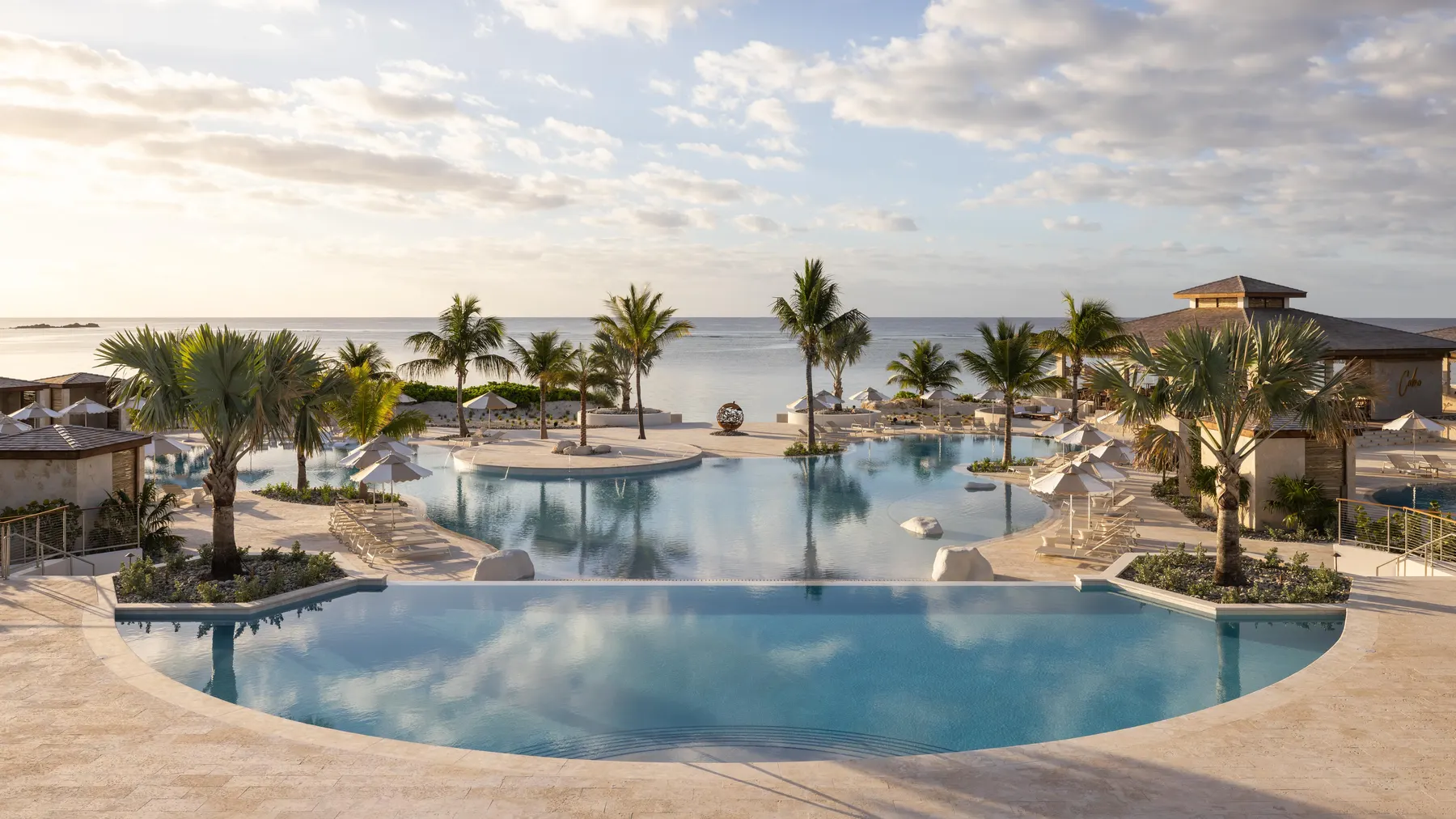 a pool with palm trees and a beach in the background