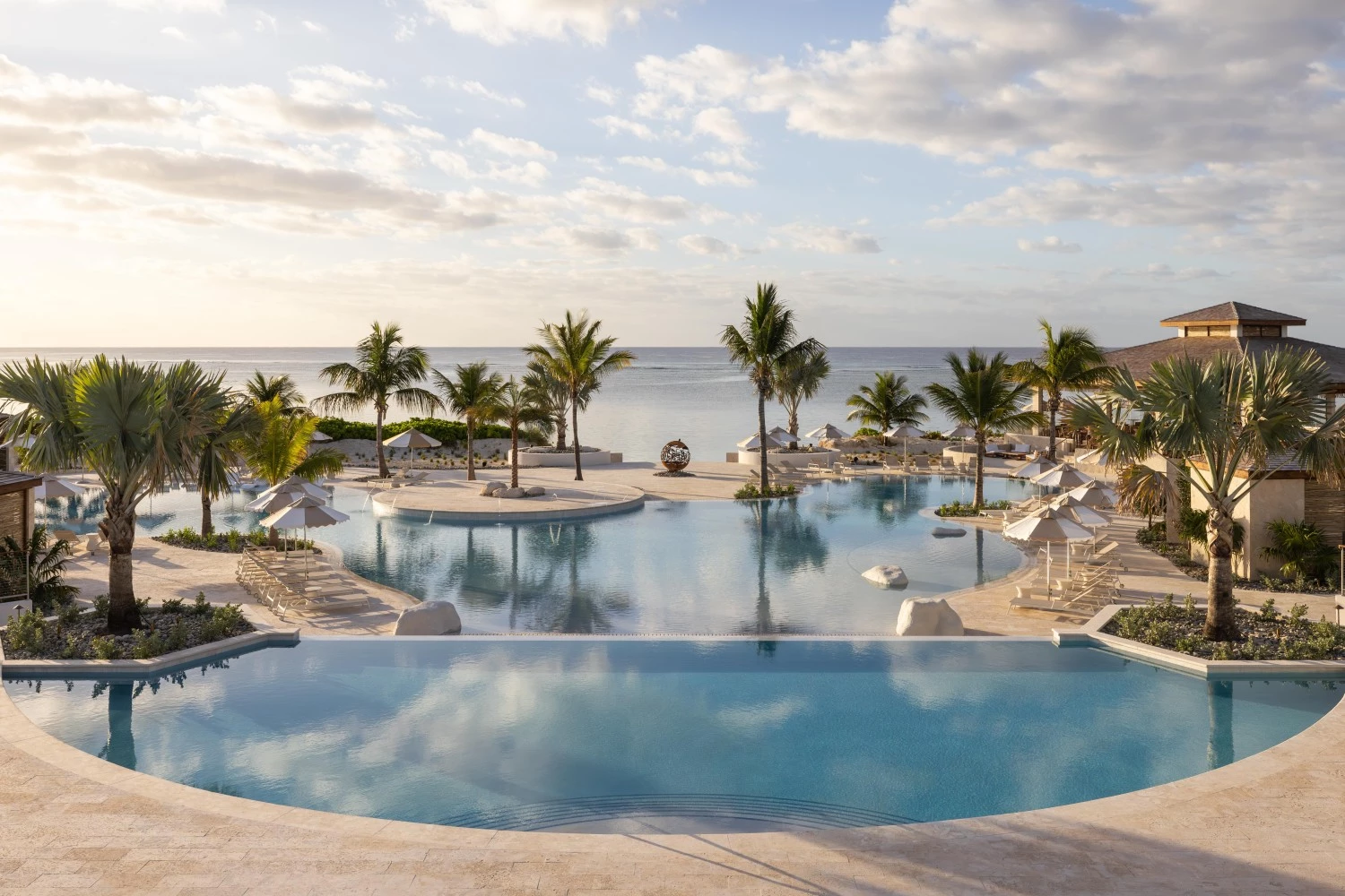 a pool with palm trees and a beach in the background